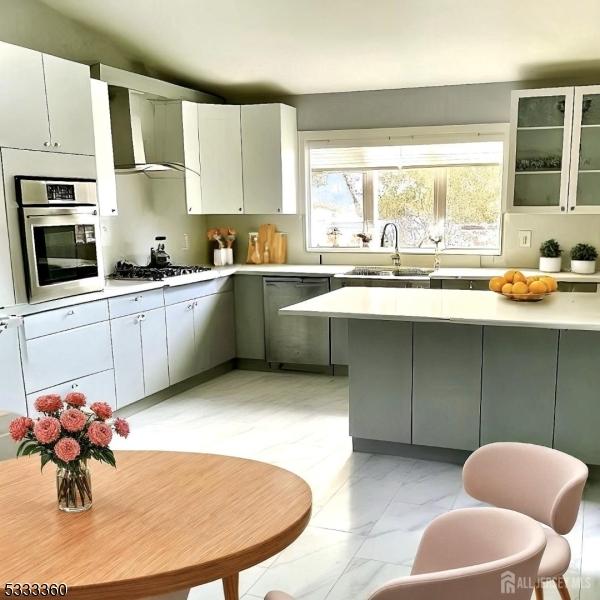 kitchen featuring appliances with stainless steel finishes, wall chimney exhaust hood, white cabinetry, sink, and gray cabinetry