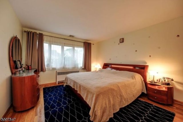 bedroom with radiator heating unit and hardwood / wood-style flooring