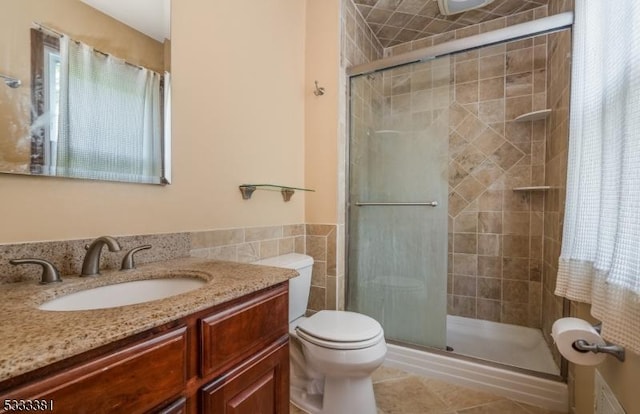 bathroom with a shower with shower door, vanity, tile walls, and toilet