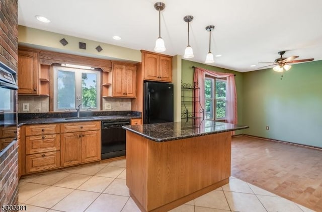 kitchen featuring decorative backsplash, light tile patterned flooring, a kitchen island, black appliances, and sink