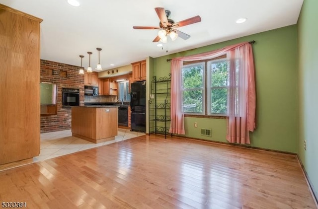 kitchen featuring black appliances, a center island, decorative light fixtures, a kitchen bar, and light wood-type flooring