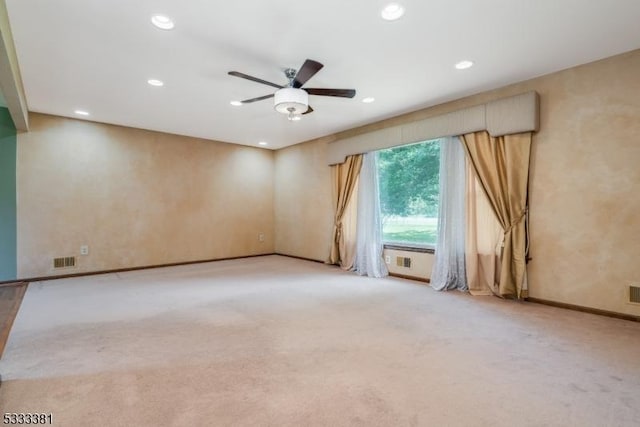 empty room featuring ceiling fan and light colored carpet