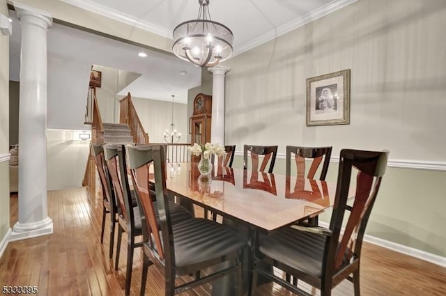 dining room with wood-type flooring, crown molding, ornate columns, and a chandelier