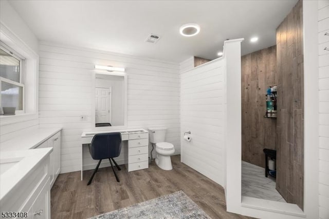 bathroom with vanity, toilet, hardwood / wood-style floors, and wood walls