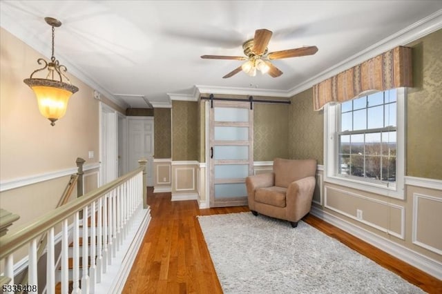 living area featuring crown molding, a barn door, ceiling fan, and hardwood / wood-style flooring