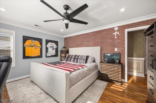 bedroom featuring ornamental molding, brick wall, wood-type flooring, and ceiling fan