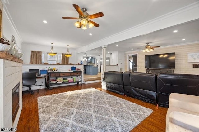 living room with ornate columns, crown molding, dark hardwood / wood-style floors, ceiling fan, and a tiled fireplace