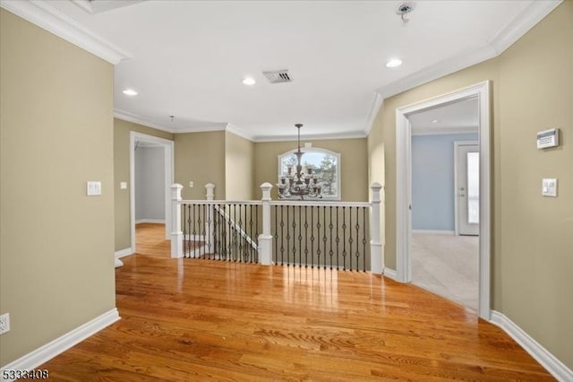 hall with hardwood / wood-style flooring, crown molding, and a notable chandelier