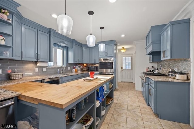 kitchen with blue cabinetry, sink, butcher block countertops, hanging light fixtures, and stainless steel appliances