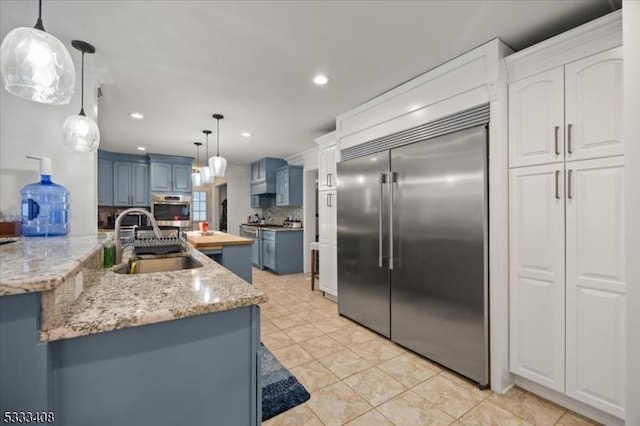 kitchen featuring sink, blue cabinetry, appliances with stainless steel finishes, white cabinetry, and decorative light fixtures