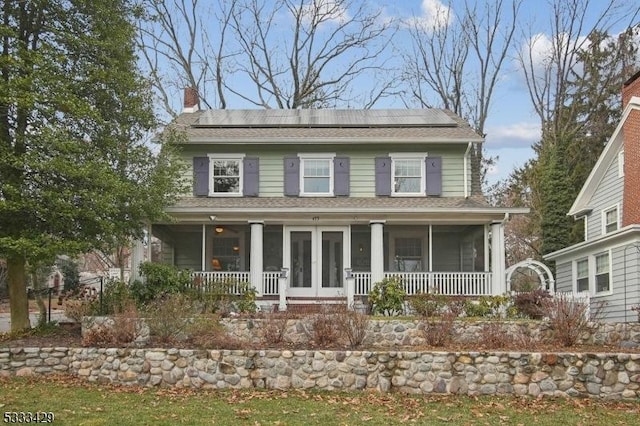 view of front of house with french doors, solar panels, and a porch