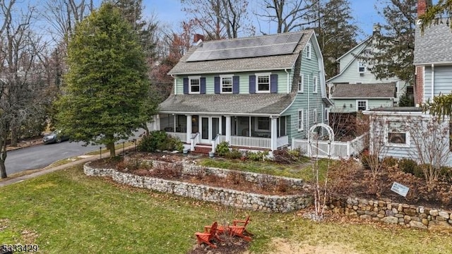 view of front of property with a front lawn, a sunroom, and solar panels