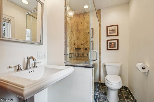 bathroom with sink, a shower with shower door, and toilet