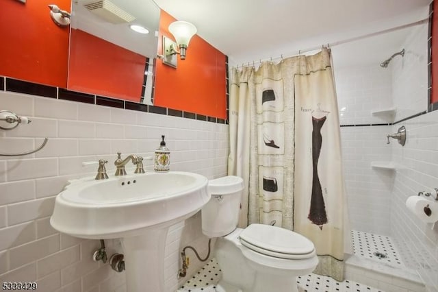 bathroom with tile walls, sink, a shower with curtain, and toilet