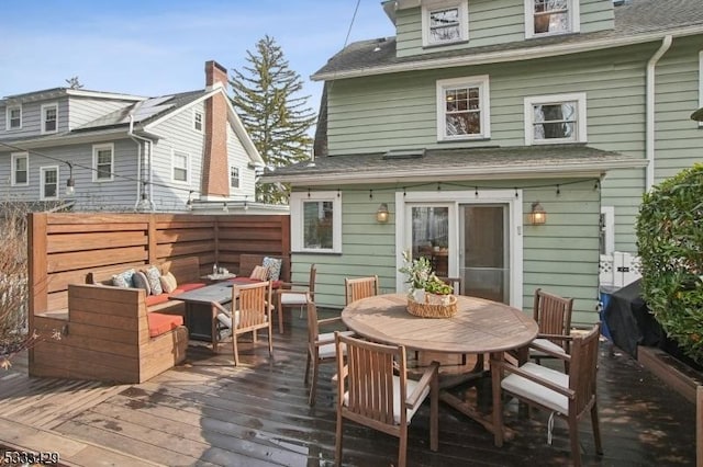 back of property with an outdoor living space with a fire pit and a deck