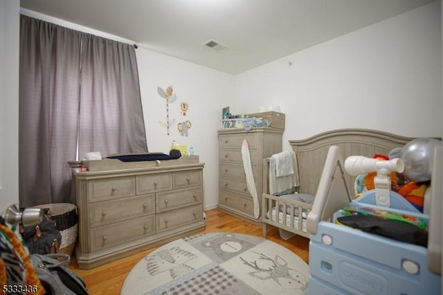 bedroom with light hardwood / wood-style floors and a crib