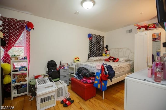 bedroom with hardwood / wood-style flooring and fridge