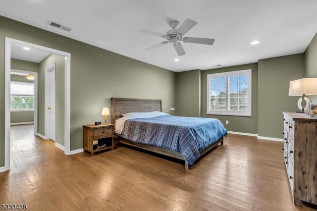 bedroom featuring ceiling fan, multiple windows, and wood-type flooring