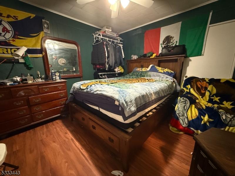 bedroom featuring hardwood / wood-style flooring, crown molding, and ceiling fan