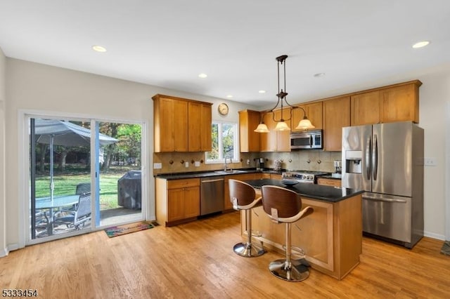 kitchen featuring pendant lighting, a center island, decorative backsplash, light hardwood / wood-style flooring, and stainless steel appliances