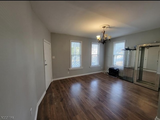 spare room featuring dark hardwood / wood-style flooring and a chandelier