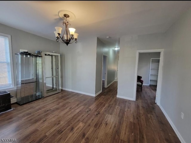 unfurnished dining area featuring a notable chandelier, plenty of natural light, and dark hardwood / wood-style floors