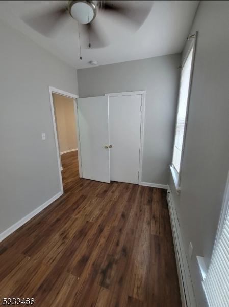 unfurnished bedroom with ceiling fan, dark hardwood / wood-style flooring, and a closet