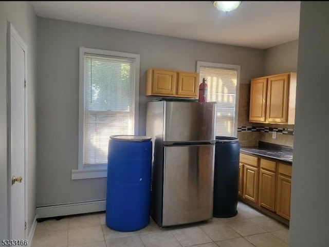 kitchen featuring a baseboard radiator, a wealth of natural light, stainless steel fridge, and tasteful backsplash