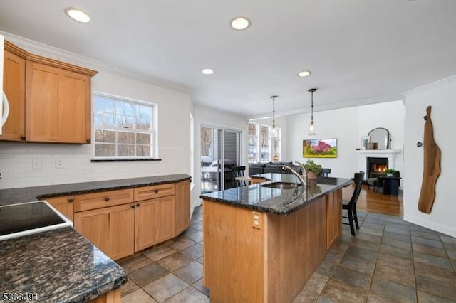 kitchen with sink, crown molding, decorative light fixtures, and an island with sink