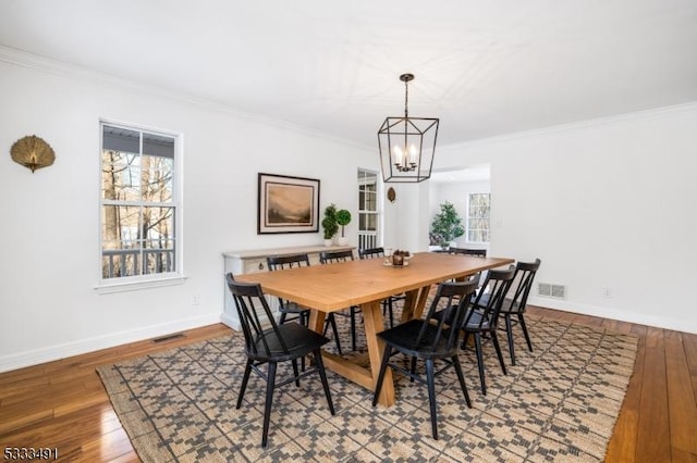 dining space featuring crown molding, wood-type flooring, and a notable chandelier