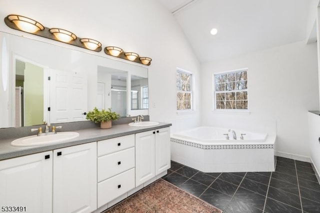 bathroom featuring a relaxing tiled tub, vanity, tile patterned floors, and lofted ceiling