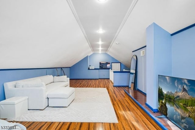 living room featuring hardwood / wood-style flooring, lofted ceiling, and crown molding