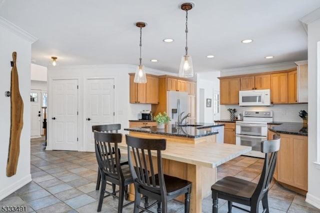 kitchen with sink, white appliances, a kitchen island with sink, backsplash, and a kitchen bar