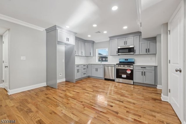 kitchen with tasteful backsplash, light wood-type flooring, gray cabinets, and stainless steel appliances