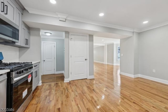 kitchen featuring crown molding, light wood-type flooring, appliances with stainless steel finishes, and gray cabinetry