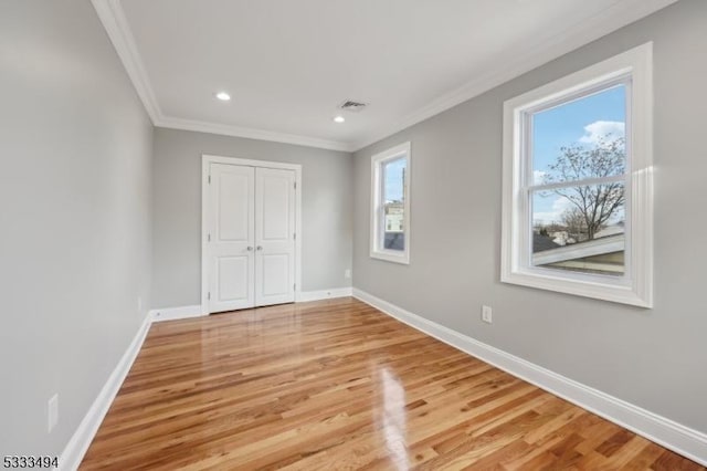 unfurnished bedroom featuring light wood-type flooring, ornamental molding, and multiple windows