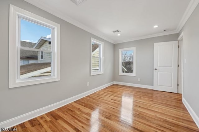 empty room featuring plenty of natural light, crown molding, and light hardwood / wood-style flooring