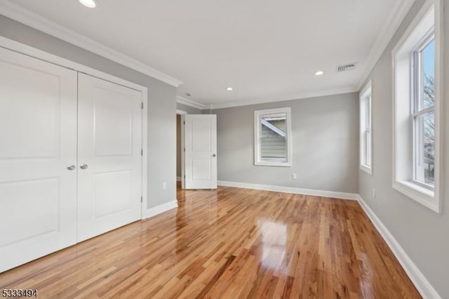 unfurnished bedroom featuring a closet, crown molding, and light hardwood / wood-style floors