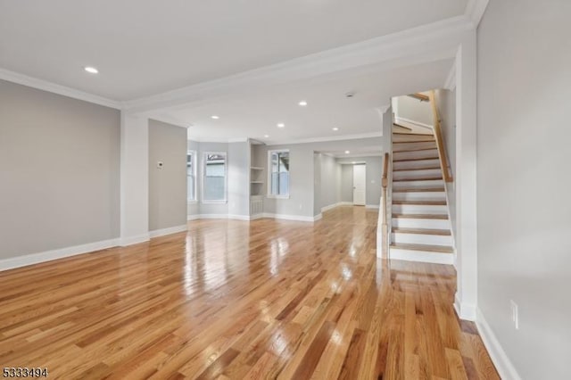 unfurnished living room featuring built in shelves, light wood-type flooring, and ornamental molding