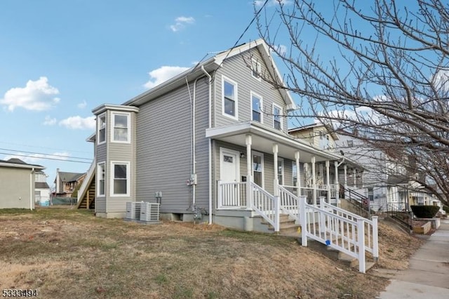 view of front facade with a front lawn, a porch, and central AC