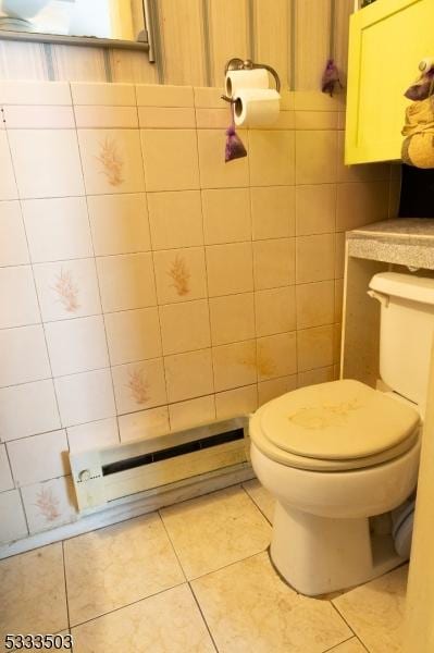 bathroom featuring toilet, tile patterned flooring, a baseboard heating unit, and tile walls