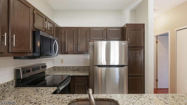 kitchen featuring sink, light stone counters, appliances with stainless steel finishes, and tasteful backsplash