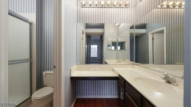 bathroom with hardwood / wood-style floors, toilet, vanity, and walk in shower