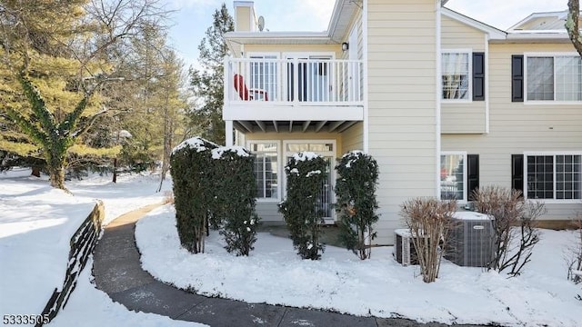 snow covered property featuring a balcony and central AC