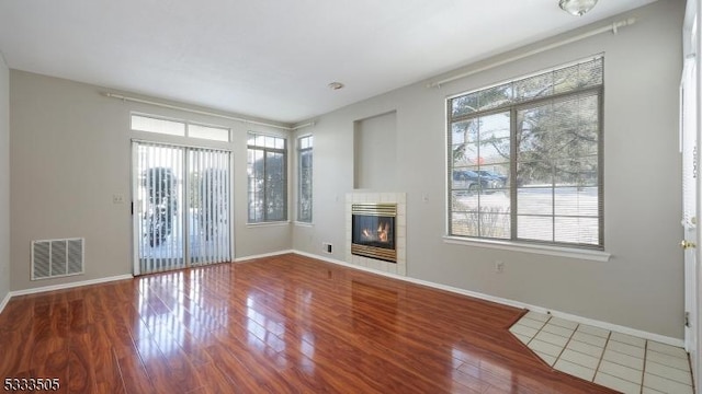 unfurnished living room with wood-type flooring and a tile fireplace