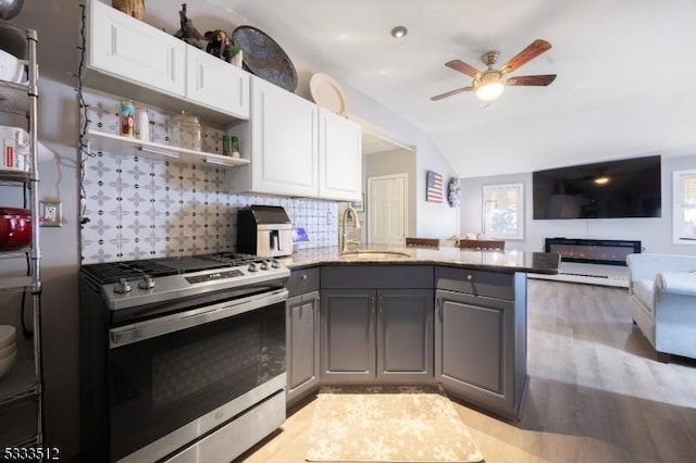 kitchen with kitchen peninsula, sink, stainless steel gas range, gray cabinetry, and white cabinets