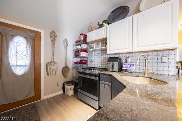 kitchen with light stone countertops, sink, white cabinets, and stainless steel gas range oven