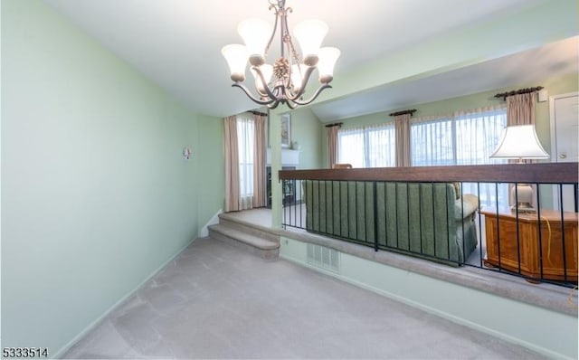 empty room with vaulted ceiling, carpet, and a notable chandelier