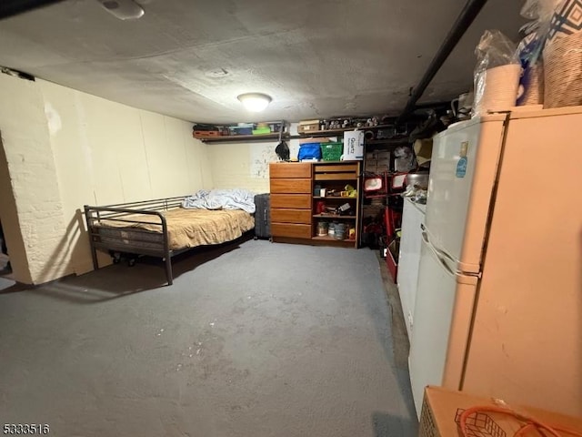 bedroom with white refrigerator and concrete floors