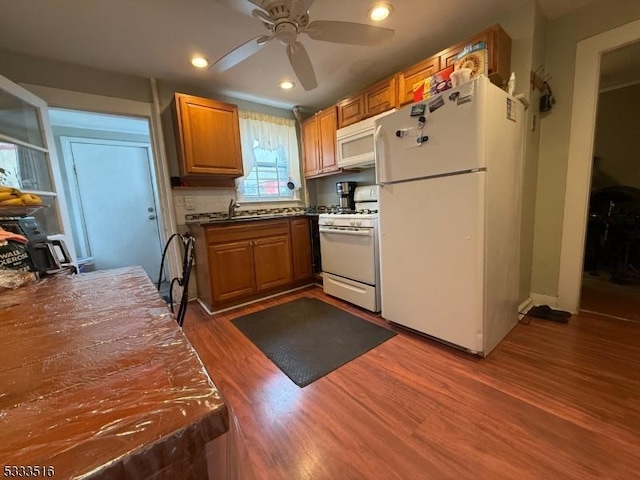 kitchen featuring ceiling fan, decorative backsplash, white appliances, dark wood-type flooring, and sink